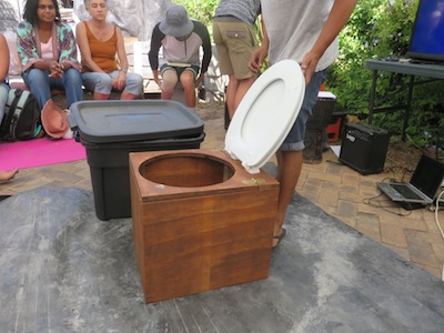 A wooden commode and a black plastic tote box which was turned into a toilet in about 15 minutes from scratch.