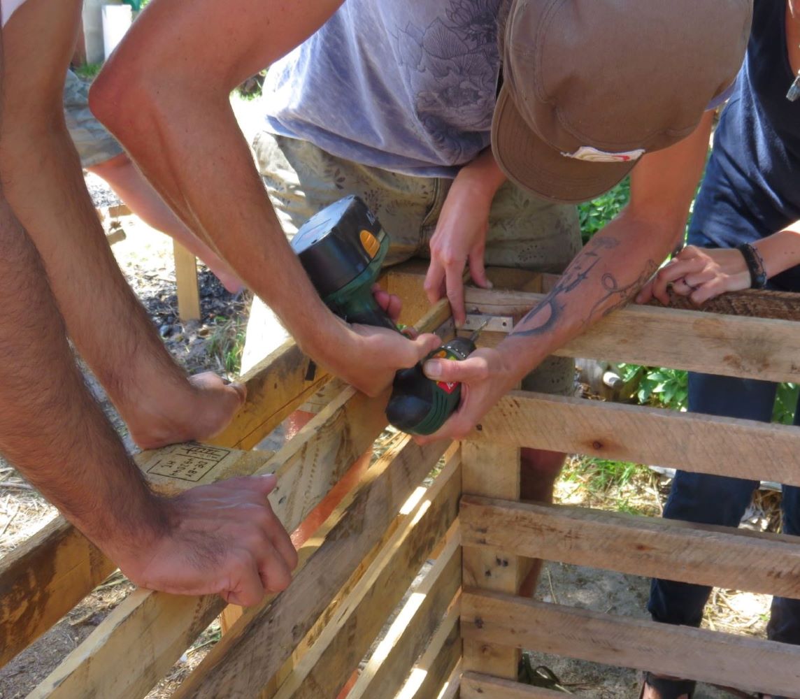 How to save drinking water from becoming black water. Use dry or compost toilets. Here volunteers work on assembling a composting box from pallets.