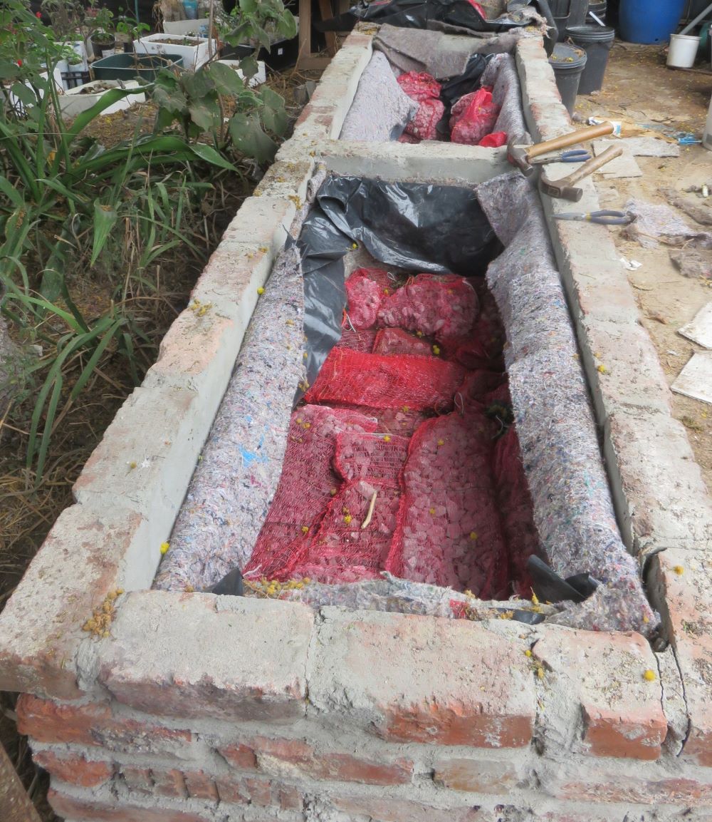 The raised wicking beds are built, lined, and filled with gravel in bags, waiting for the water to back up. The next stage is filling the tanks with soil and plants.